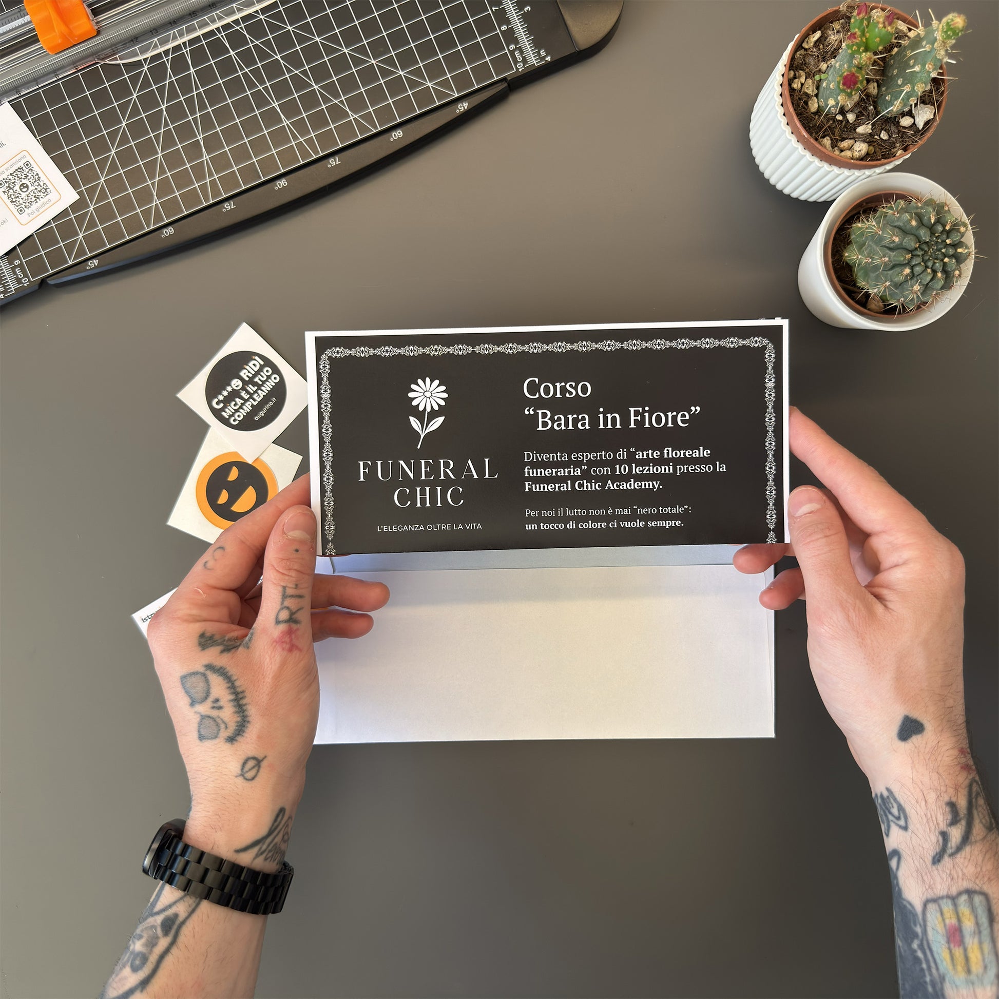 Foto prodotto del finto voucher per il corso per diventare esperti di arte floreale funeraria tenuto tra le mani