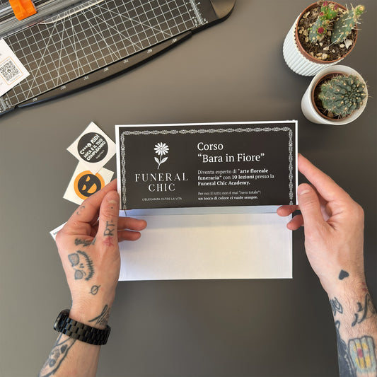 Foto prodotto del finto voucher per il corso per diventare esperti di arte floreale funeraria tenuto tra le mani