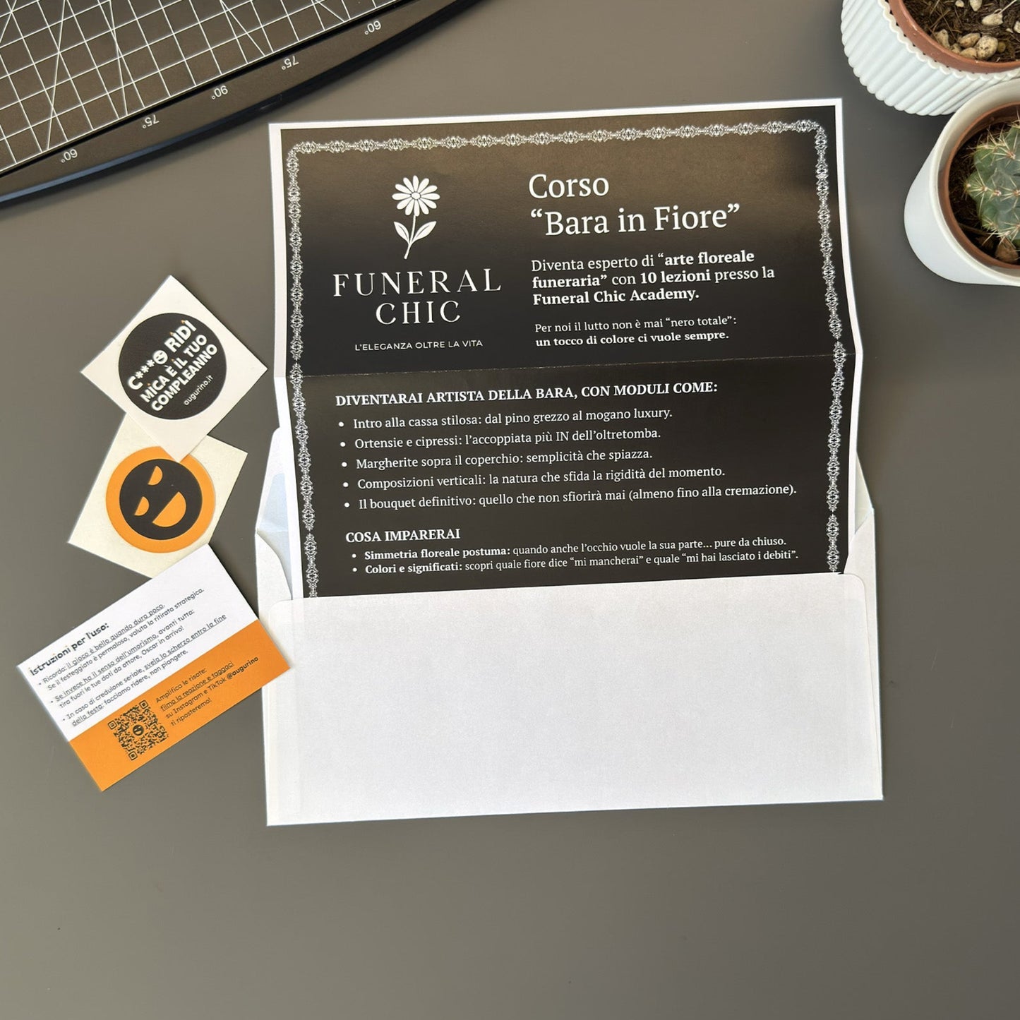 Foto prodotto del finto voucher per il corso per diventare esperti di arte floreale funeraria con busta per lettere